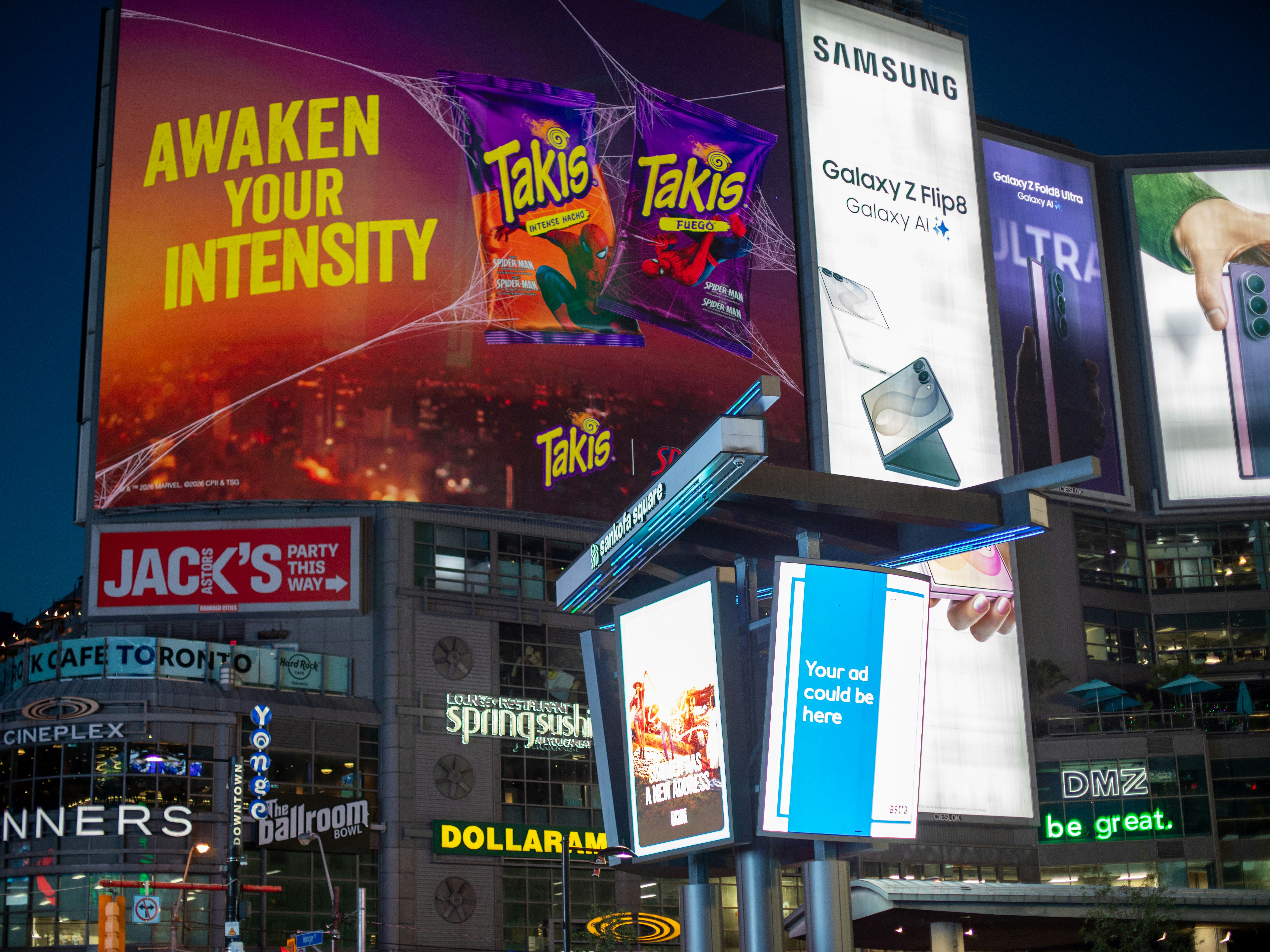 Bright digital billboards illuminate a city square at night